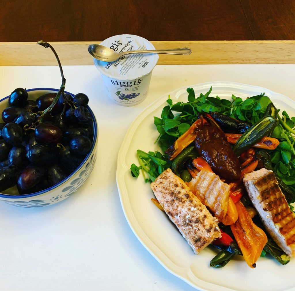 Healthy dinner with salmon, salad, grapes and yogurt