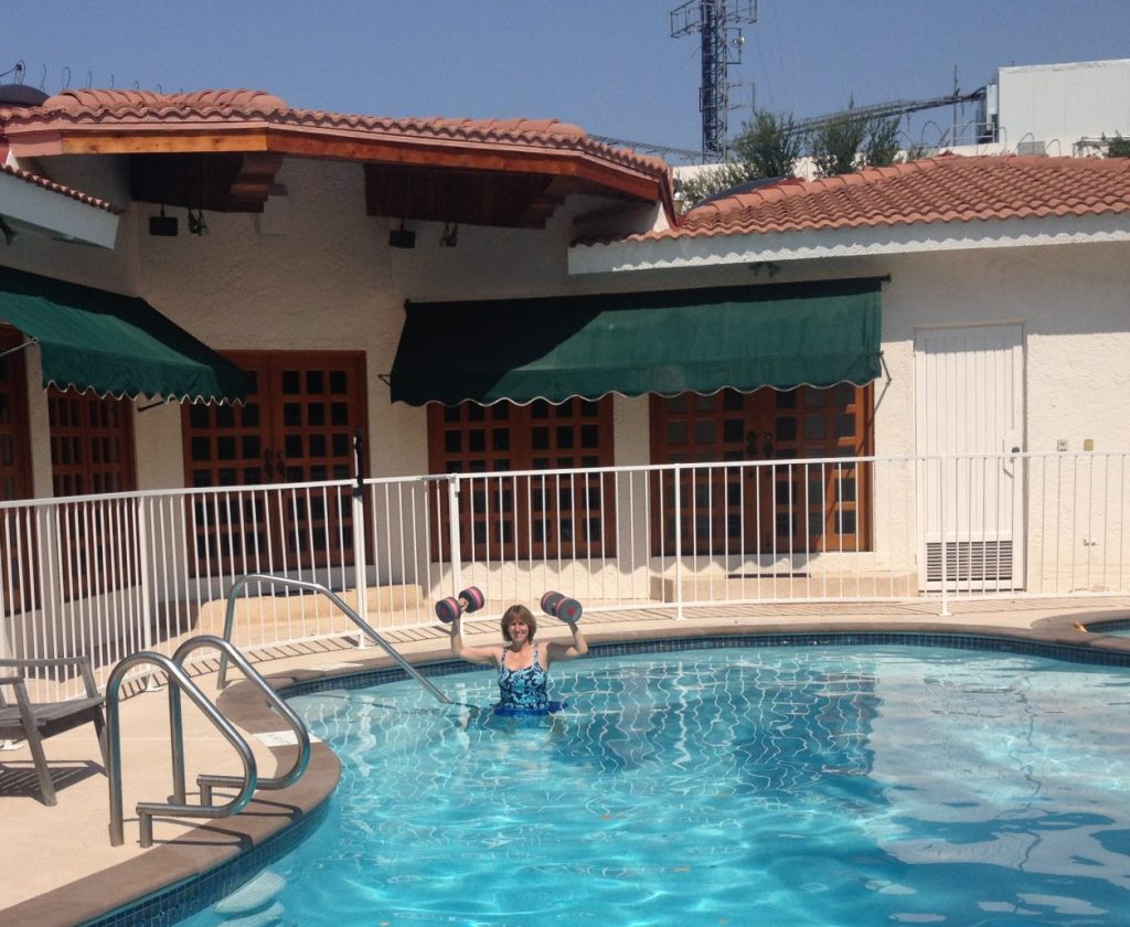 The author in her pool in Mexico, holding up foam dumbbells