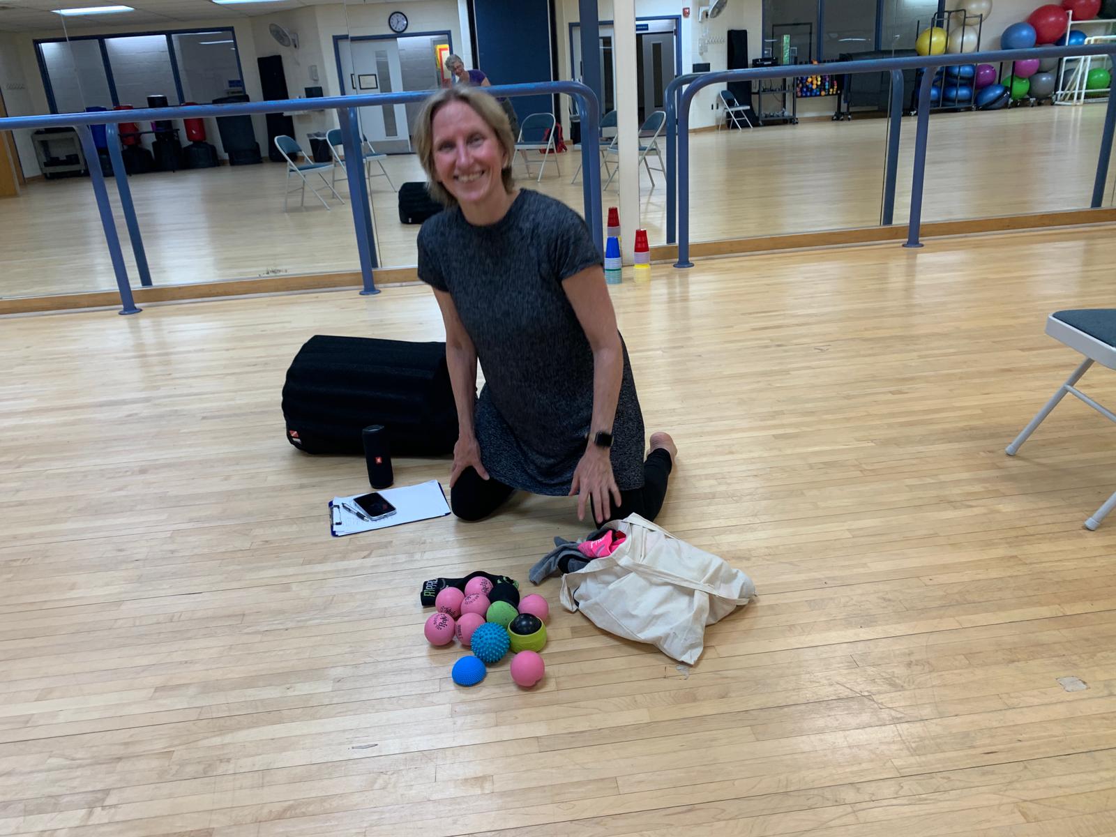 The author sitting on the floor in the rec center classroom with her props